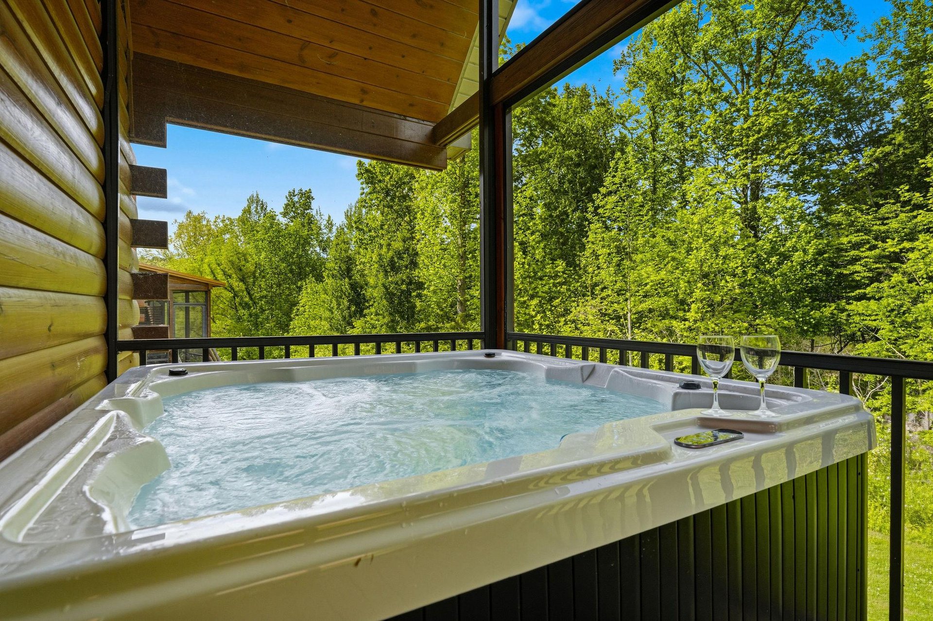 Soak in your private hot tub overlooking lush forest views—a perfect moment to unwind with a glass of wine surrounded by natures tranquility.