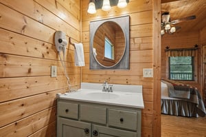 Step into rustic charm with warm woodpaneled walls and your own cozy vanity space, complete with a stylish round mirror and convenient hair dryer.
