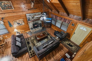 Your spacious cabin living room invites you to relax by the stone fireplace beneath soaring woodbeamed ceilings. Plush leather sofas and rustic décor create the perfect cozy retreat after a day outdo