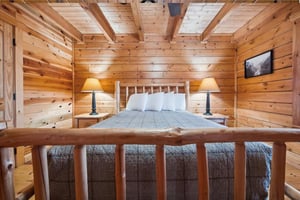 Drift off in your cozy log cabin bedroom, where warm wood surrounds you and soft lamplight creates the perfect ambiance for peaceful nights.