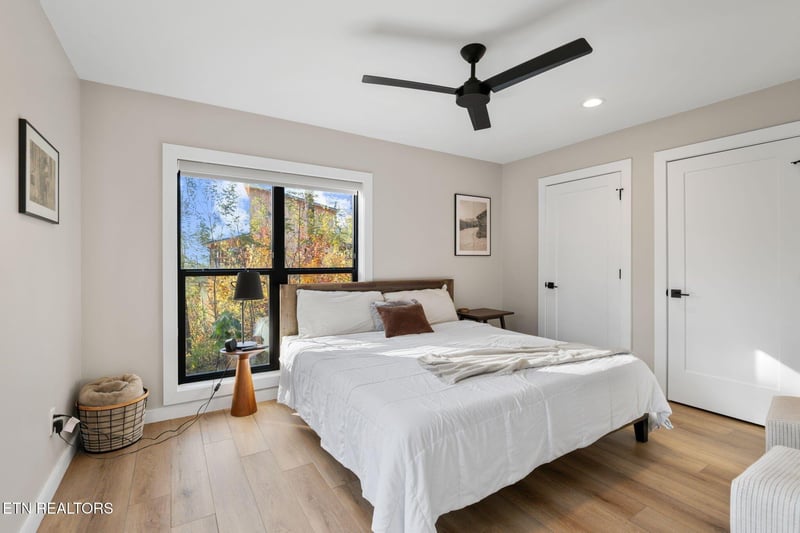 Drift off to sleep in this serene bedroom, where natural light streams through the large window and a gentle ceiling fan keeps your space perfectly comfortable.