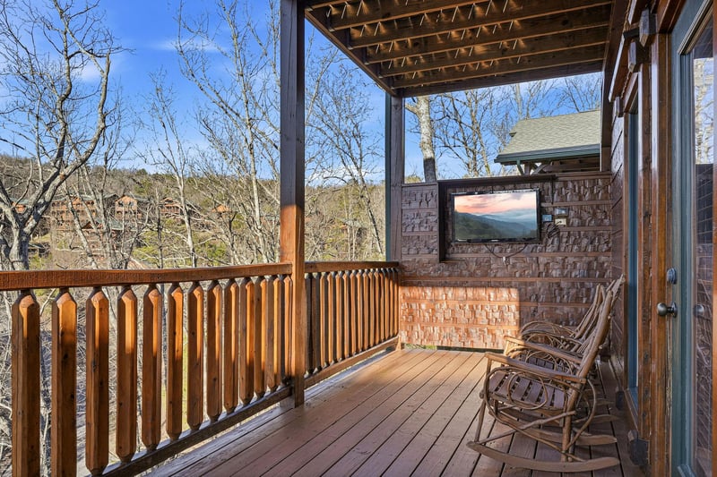 Your private covered balcony overlooks a peaceful wooded hillside, offering serene mountain views. The outdoor TV lets you unwind while soaking in the natural beauty surrounding you.