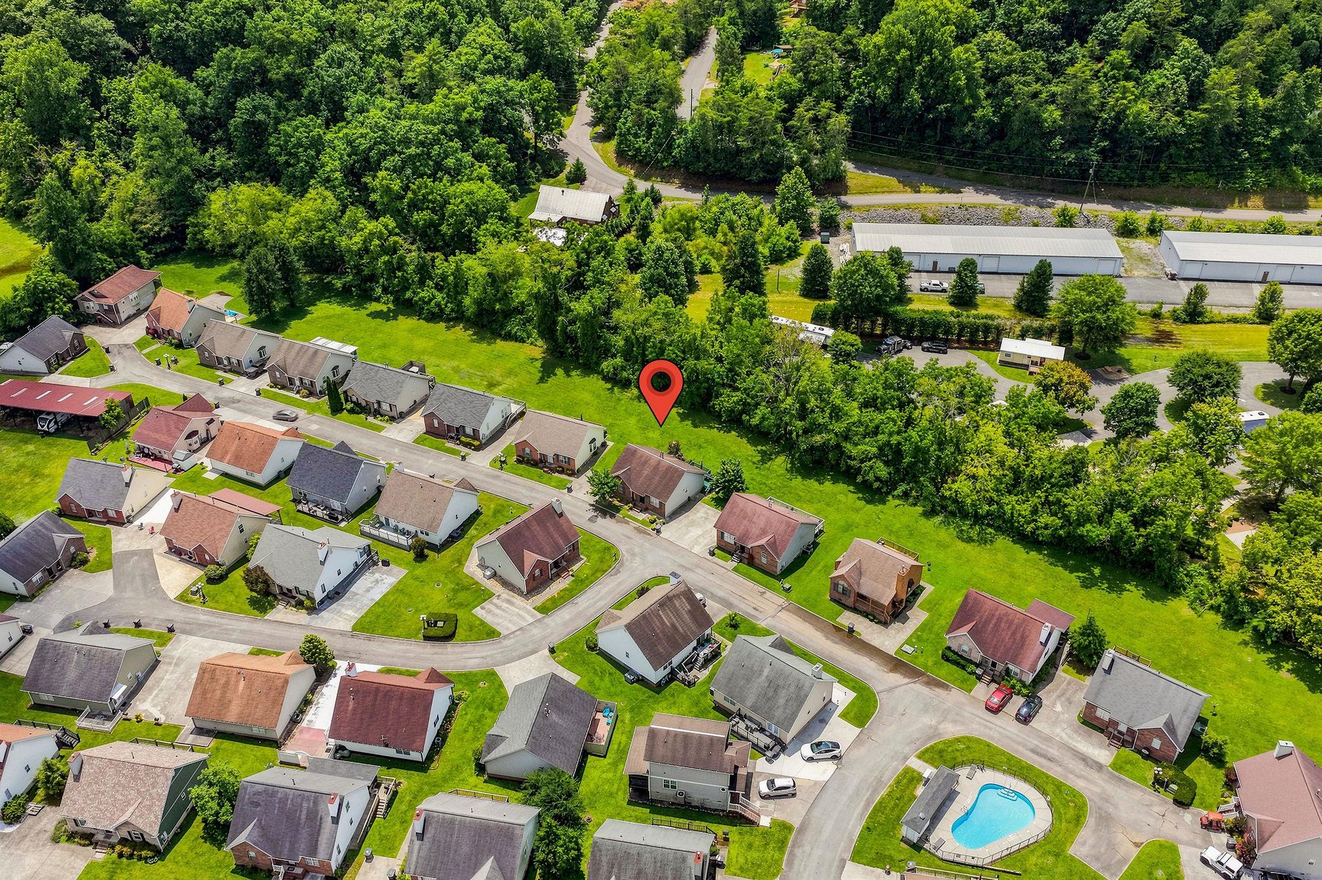 Aerial view of a peaceful residential neighborhood, surrounded by lush greenery and just minutes from local amenities—a serene retreat with convenient access to nearby roads and facilities.