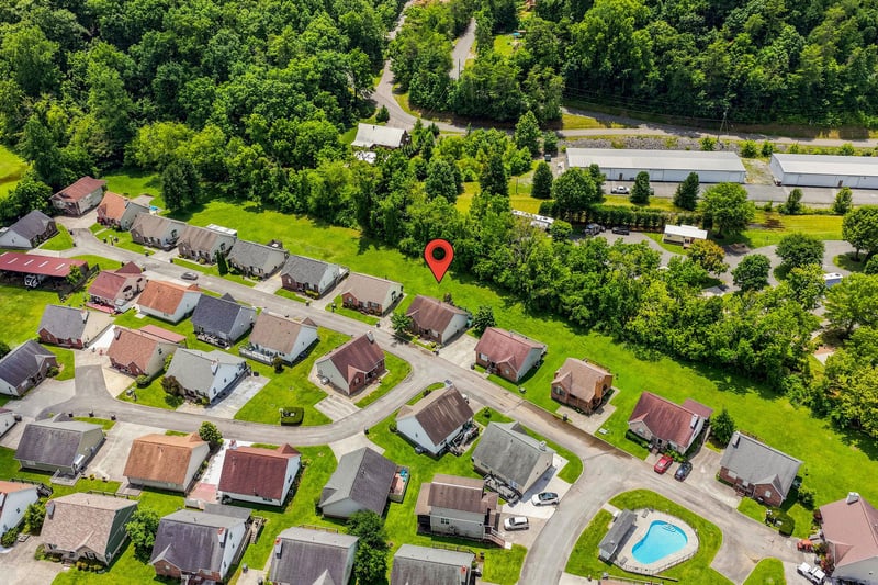 Aerial view of a peaceful residential neighborhood, surrounded by lush greenery and just minutes from local amenities—a serene retreat with convenient access to nearby roads and facilities.