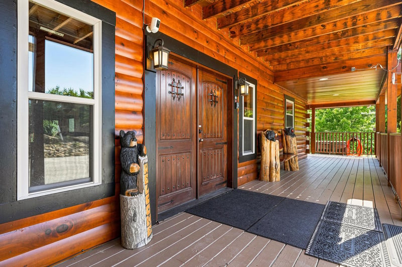 Rustic wood entrance with handcrafted details invites you into a warm mountain escape framed by lush forest views.