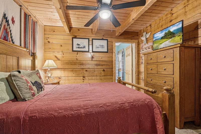 Step into your cozy cabin retreat, where warm wood walls and handcrafted touches create the perfect mountain escape. Drift off under the glow of a gentle ceiling fan in this inviting bedroom.