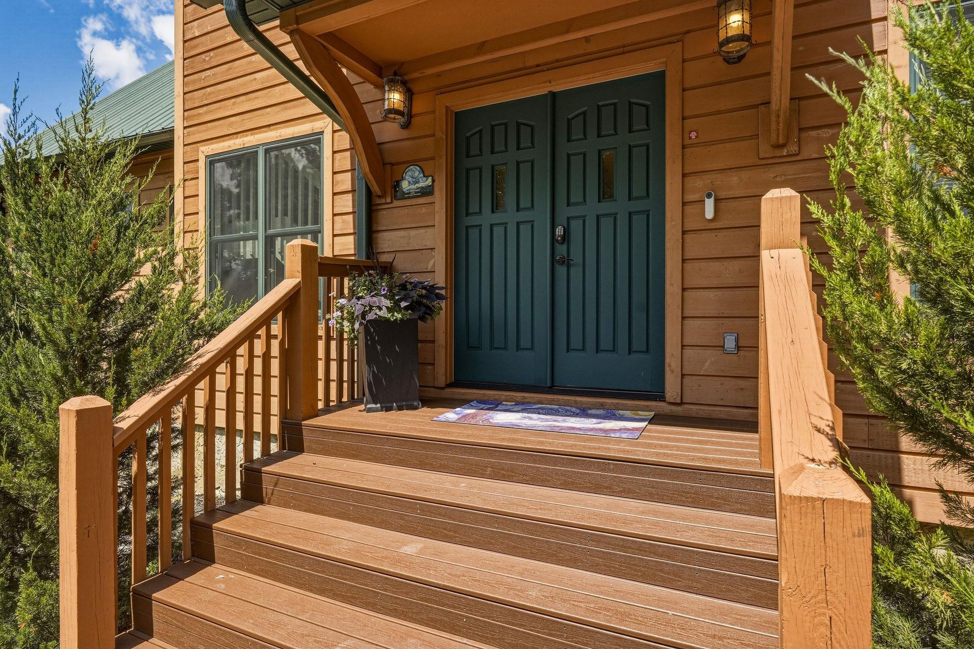 This warm cedarsided entrance welcomes you with charming lantern lighting and a covered porch framed by evergreens, setting the tone for a cozy mountain retreat.