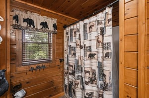Step into your charming bathroom featuring rustic woodpaneled walls, inviting natural light, and cozy wildernessthemed décor that brings the outdoors in.