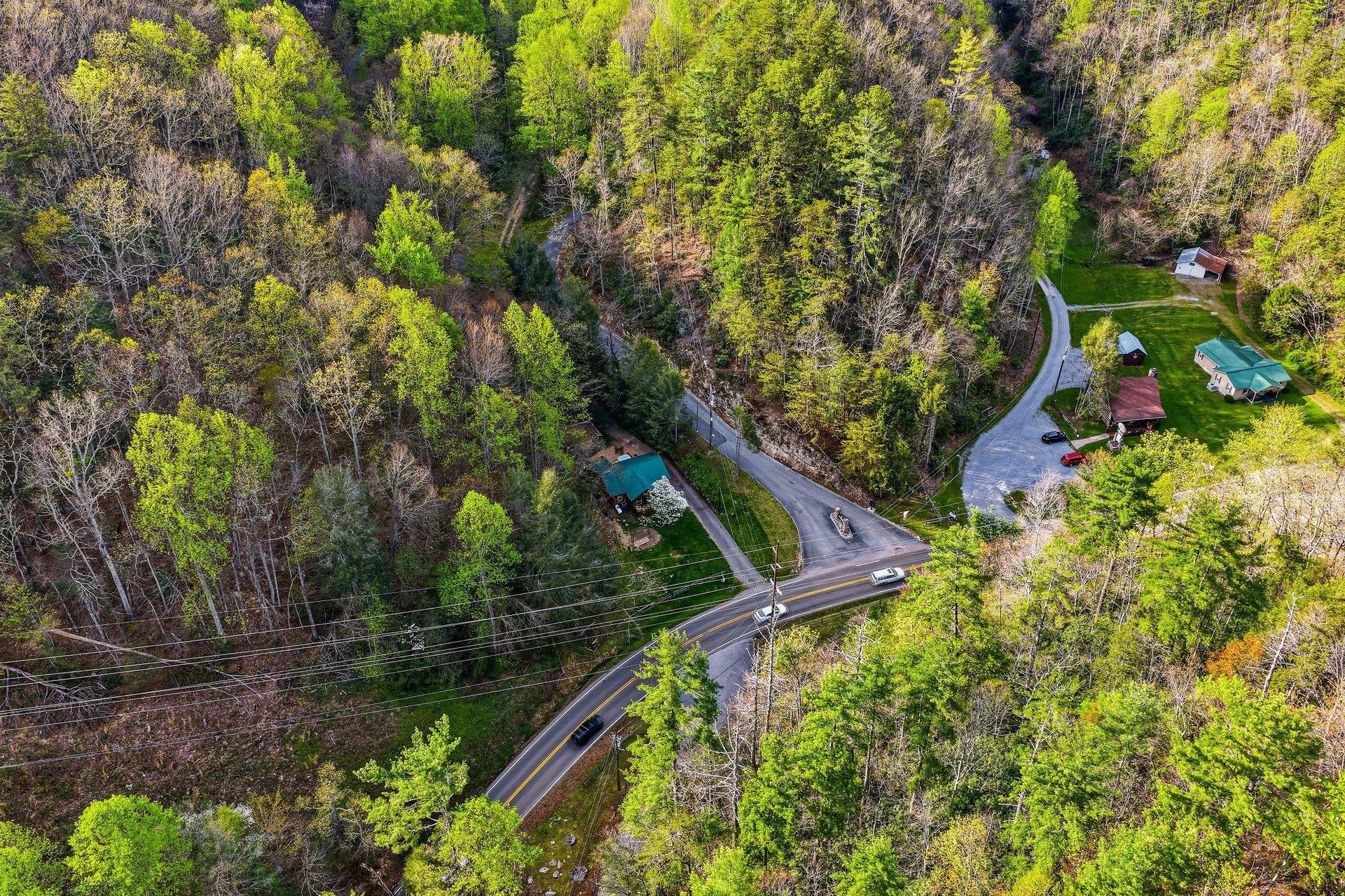 Aerial view of the property nestled in lush forest surroundings with convenient road access and peaceful natural setting.