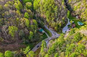 Aerial view of the property nestled in lush forest surroundings with convenient road access and peaceful natural setting.