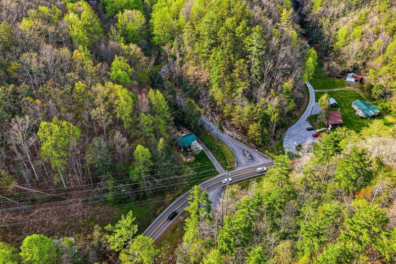 Aerial view of the property nestled in lush forest surroundings with convenient road access and peaceful natural setting.