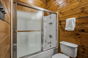 Freshen up in your cozy cabin bathroom featuring a tubshower combo with warm wood plank walls and plush towels waiting for you.
