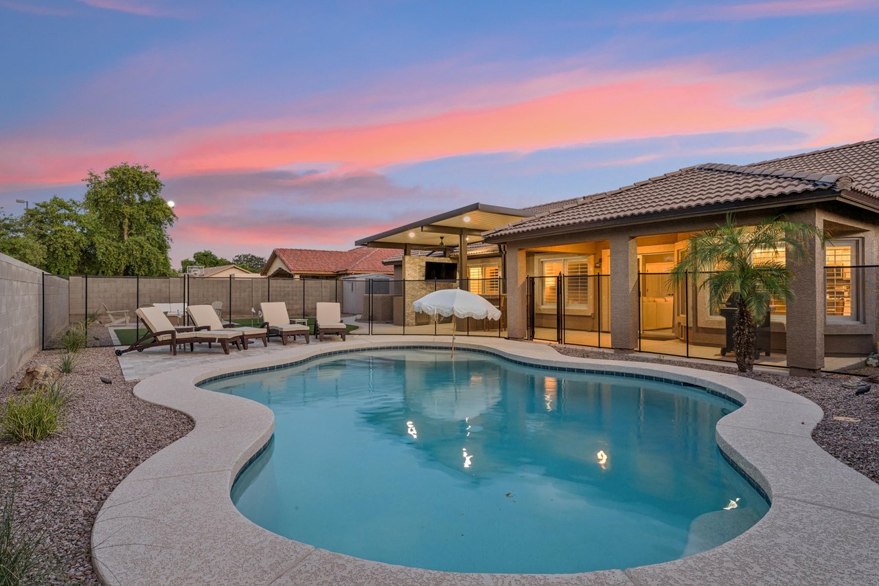 Private sparkling fenced pool with umbrella and sun loungers.