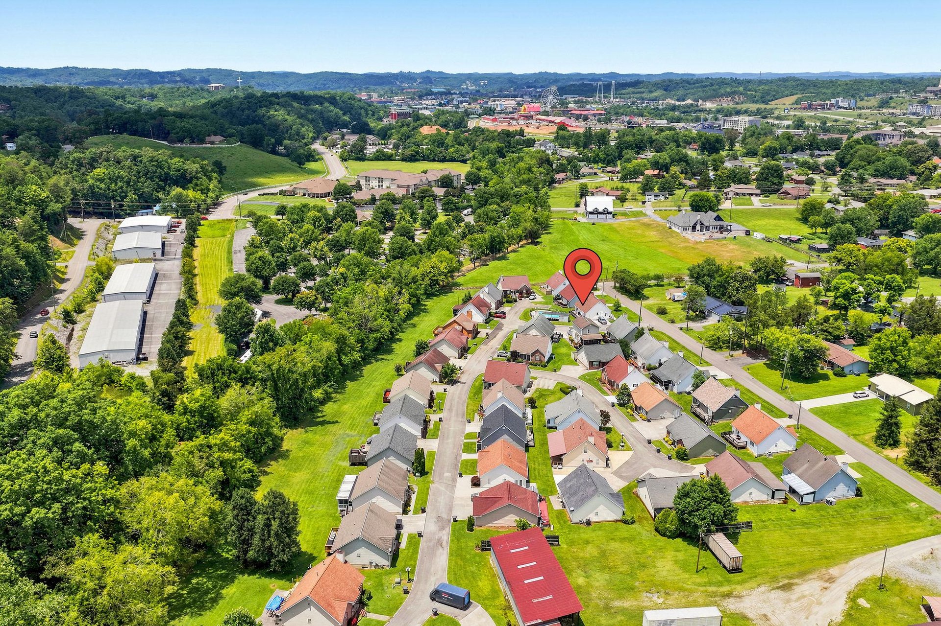 Aerial view showcasing the propertys location within a peaceful residential neighborhood, surrounded by lush green spaces and rolling hills.