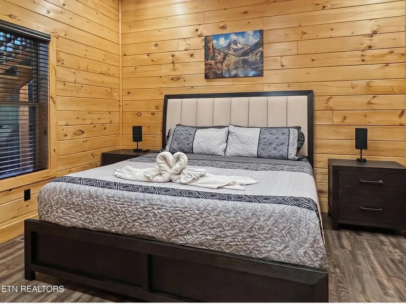 Drift off in your cozy cabin bedroom, where warm wood walls and fresh linens create the perfect mountain retreat sanctuary.