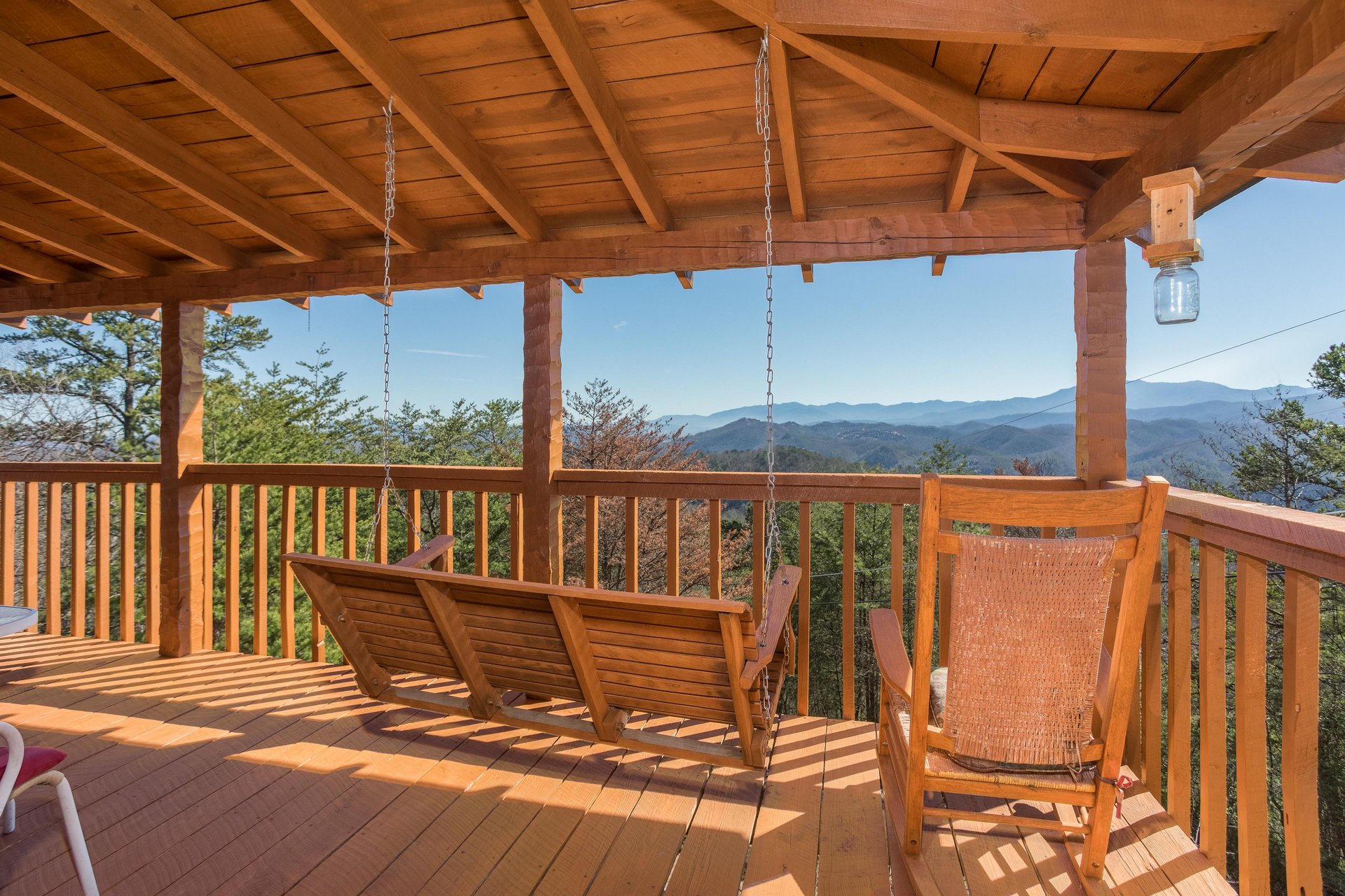 Porch swing and rocking chair on a covered deck at Mountain Glory, a 1 bedroom cabin rental located in Pigeon Forge