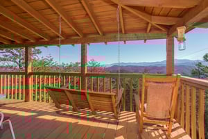 Porch swing and rocking chair on a covered deck at Mountain Glory, a 1 bedroom cabin rental located in Pigeon Forge