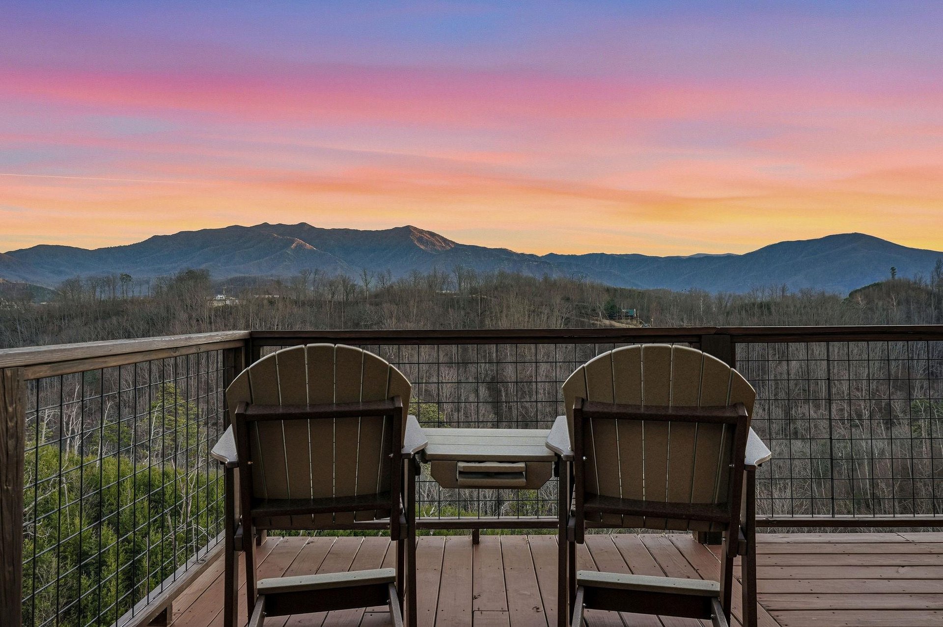 Sunset paints the sky in brilliant purples and gold as mountain silhouettes frame your private balcony retreat.