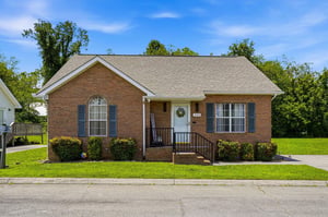 Charming brick rental situated in a peaceful neighborhood, surrounded by mature trees and open green space, offering a welcoming exterior with easy street access.