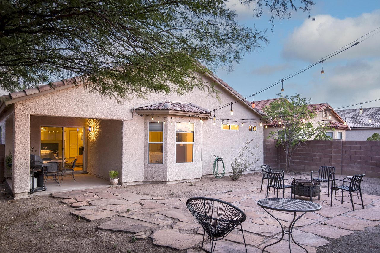 Just off the back patio is the fully enclosed outdoor space with string lights, a fire pit, and additional outdoor seating.