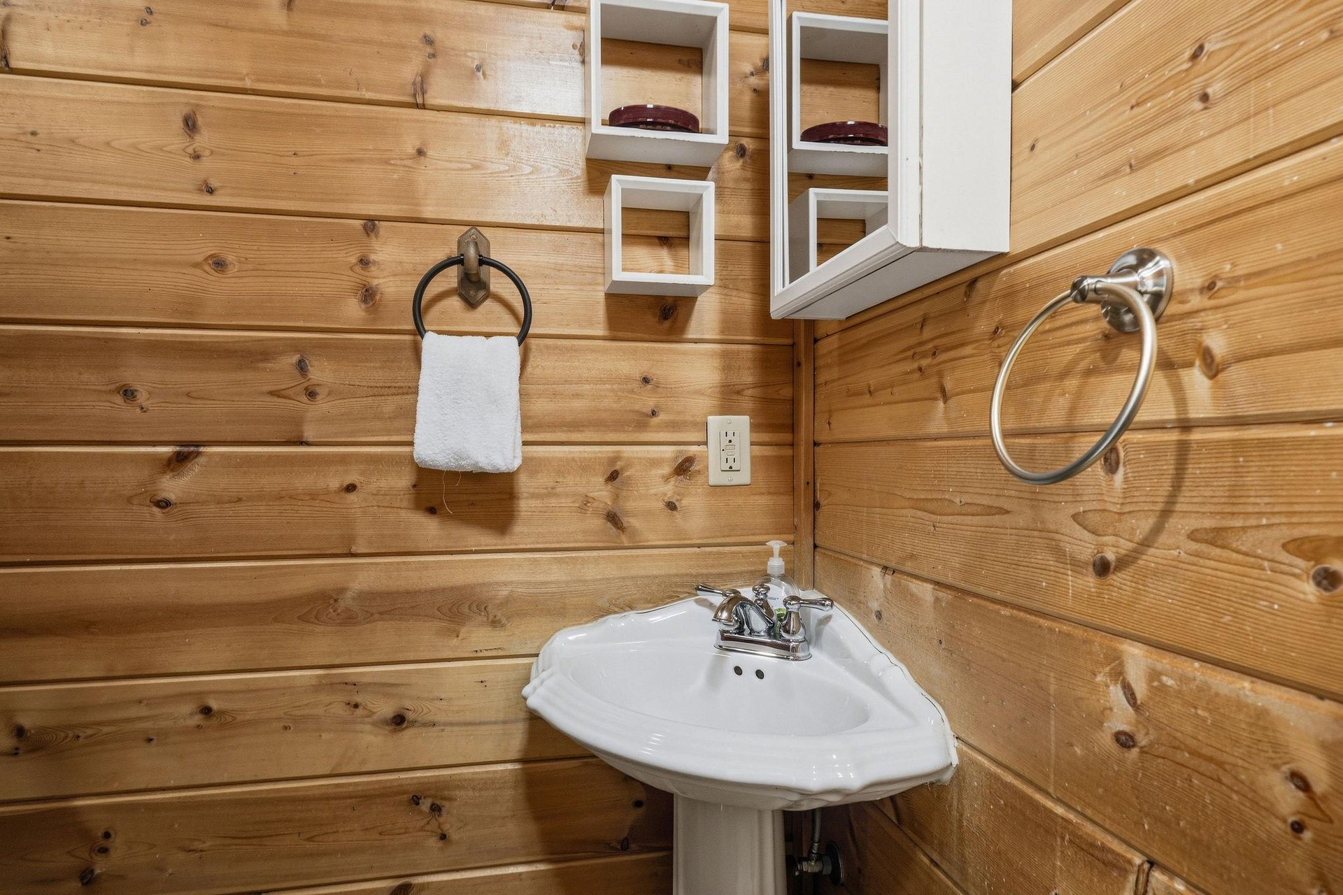 Refresh in your rustic bathroom with warm wood walls and convenient storage shelves for all your essentials.