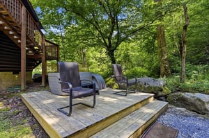 Step onto your private deck surrounded by lush forest, where two inviting chairs await your morning coffee or evening unwind beneath the trees.