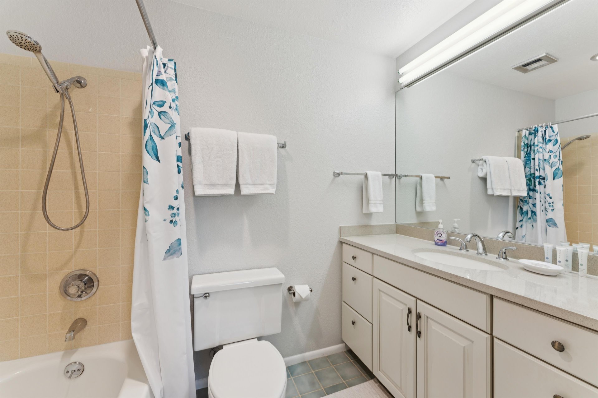 Ensuite bathroom stocked with clean linens, starter pack of amenities, and a convenient handheld showerhead.