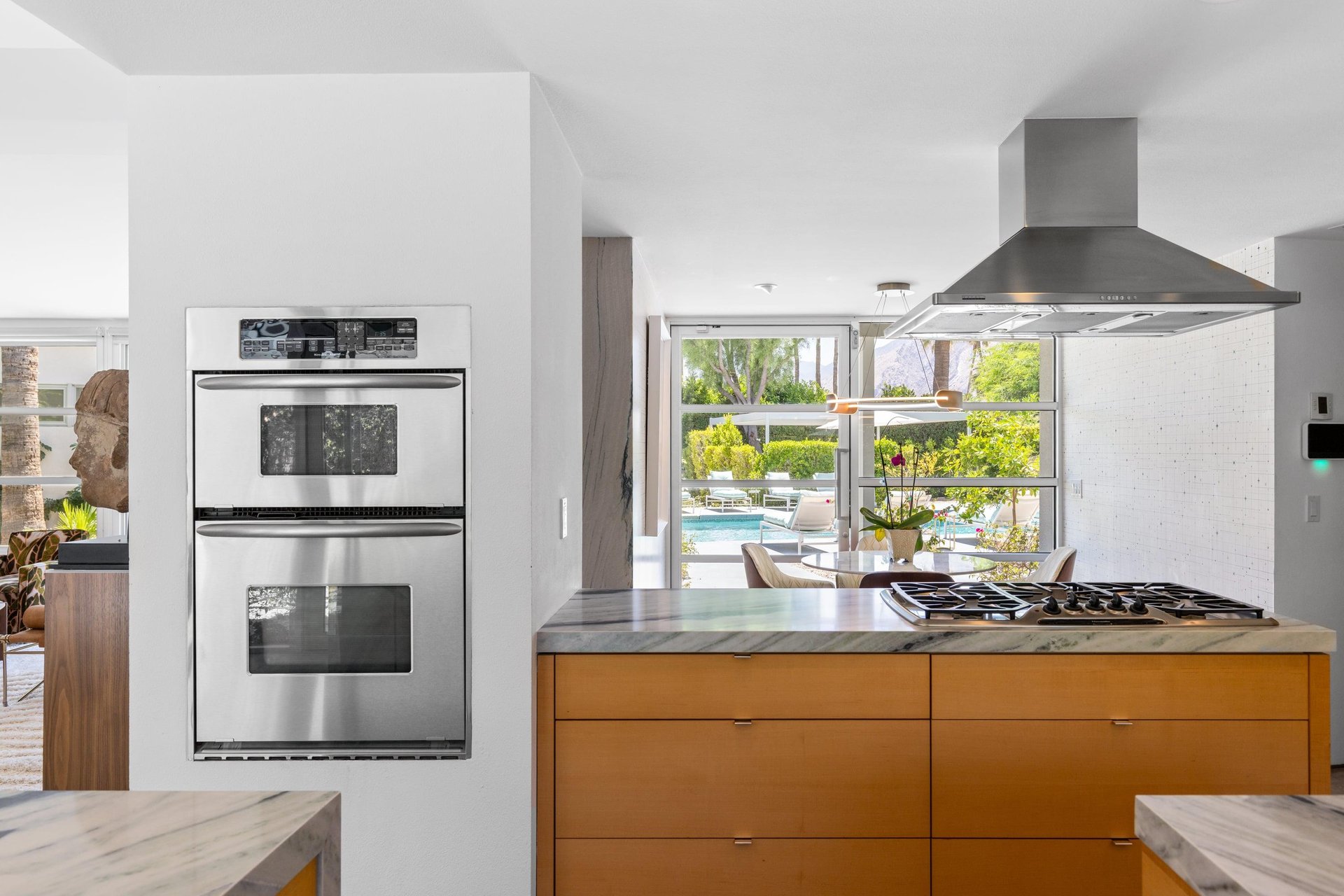 Modern chefs kitchen with a waterfall marble counter, kitchen island, stainlesssteel appliances, wine fridge, wet bar, and kitchen essentials. On the other side of the stove is where the breakfast nook can be found.