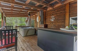 Relax on your private deck featuring a soothing hot tub surrounded by warm wood beams and forest views.