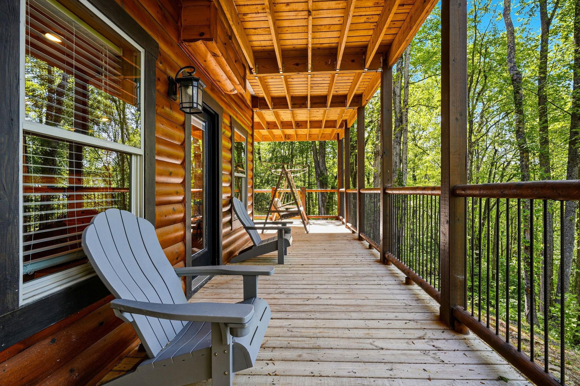 Unwind on your private covered deck with comfortable Adirondack chairs, overlooking peaceful forest views through towering trees.