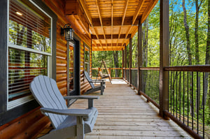Unwind on your private covered deck with comfortable Adirondack chairs, overlooking peaceful forest views through towering trees.