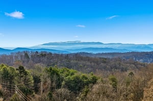 Breathtaking mountain panorama stretches across rolling blue ridges under bright sky.