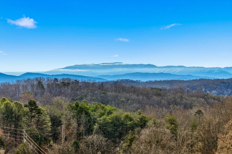 Breathtaking mountain panorama stretches across rolling blue ridges under bright sky.