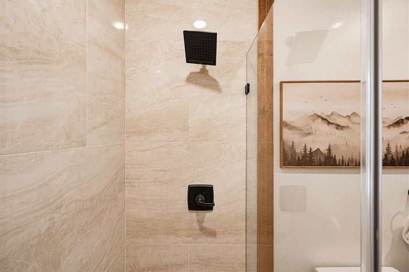 Step into your private rain shower, where warm water and sleek modern fixtures await. The elegant marblelook tiling and matte black hardware create a soothing retreat after a day of adventure.
