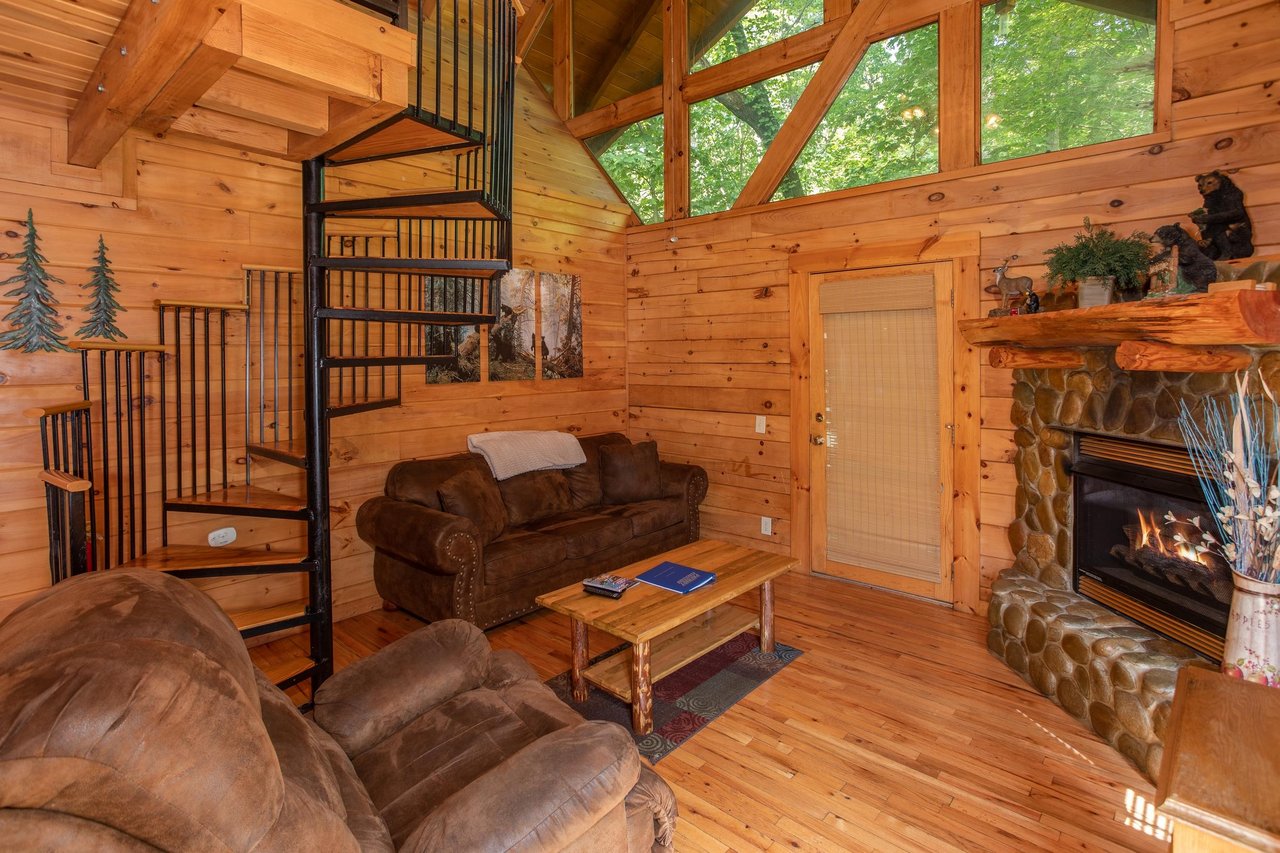 Living room with a fireplace and spiral staircase at Dreams Do Come True, a 1bedroom cabin rental located in Pigeon Forge
