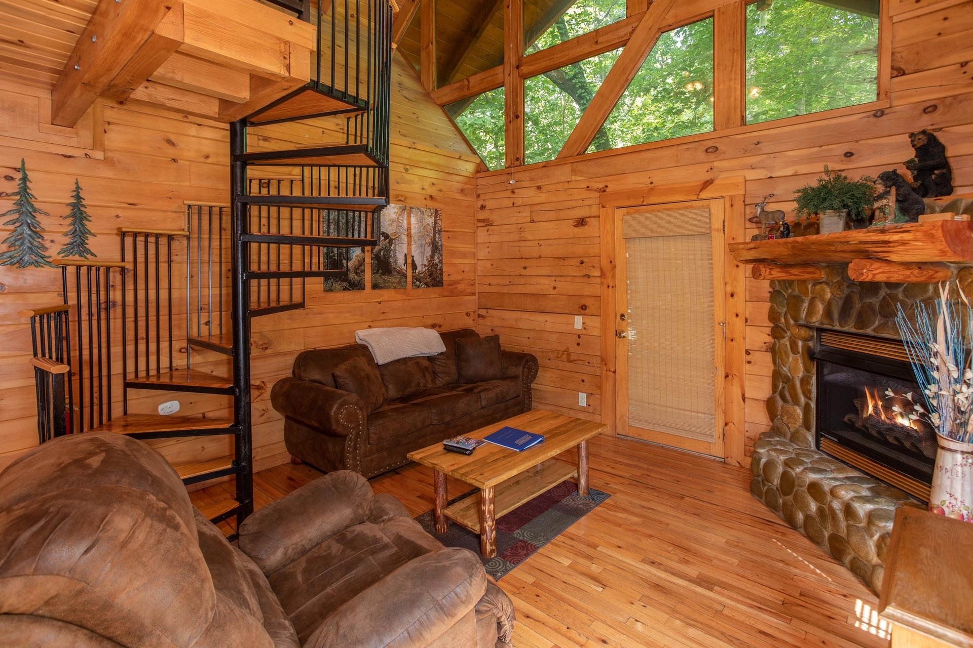 Living room with a fireplace and spiral staircase at Dreams Do Come True, a 1bedroom cabin rental located in Pigeon Forge