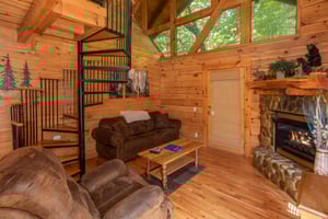 Living room with a fireplace and spiral staircase at Dreams Do Come True, a 1bedroom cabin rental located in Pigeon Forge