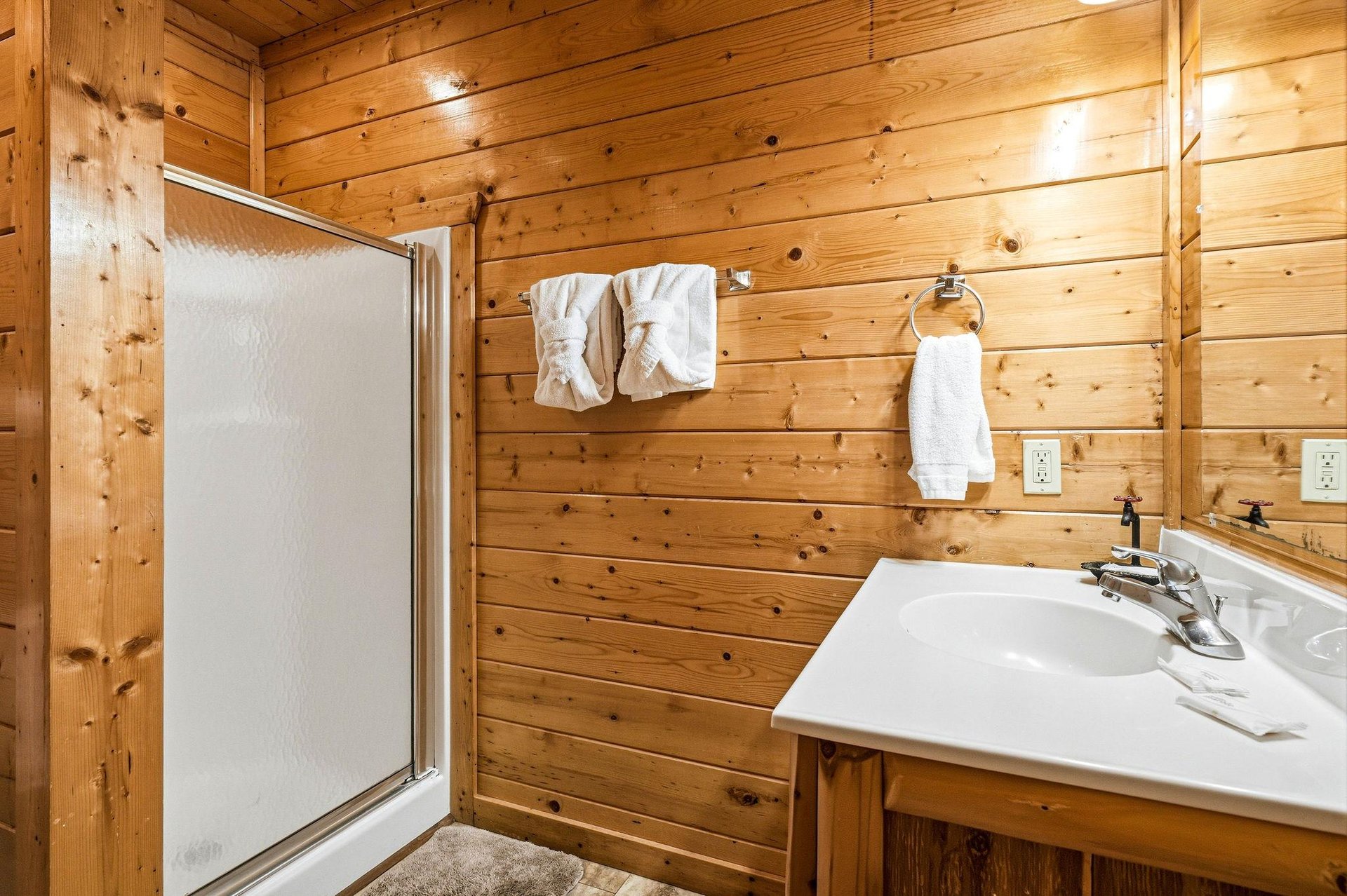 Step into a warm, rustic bathroom with natural wood walls, fresh towels waiting for you, and a private shower to refresh after your days adventures.
