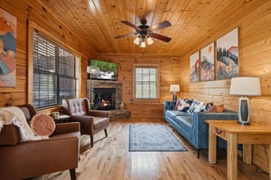 Settle into your cozy cabin living room with warm wood walls, crackling fireplace, and plush leather seating for the perfect mountain retreat.