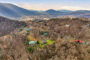 Peaceful mountain valley retreat with scattered cabins nestled among rolling hills and scenic countryside views.