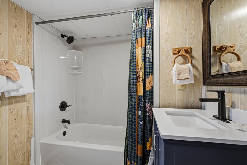 Step into your private bathroom with a full tubshower combo, crisp white fixtures, and charming rustic wood paneling that sets a cozy, cabinlike mood for your getaway.