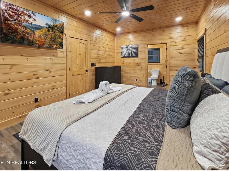 Unwind in your cozy cabin bedroom with warm wood walls, plush bedding, and charming rustic touches that make mountain getaways memorable.