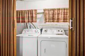 Your laundry stays fresh and convenient with a full washer and dryer set, complete with cheerful plaid curtains brightening this practical space.