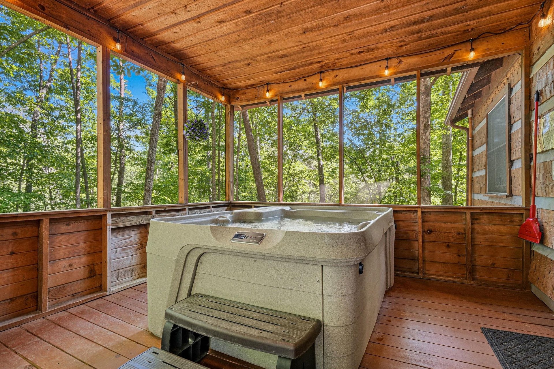 Soak in your private hot tub while surrounded by tranquil forest views through floortoceiling windows, all beneath warm string lights creating the perfect evening retreat.