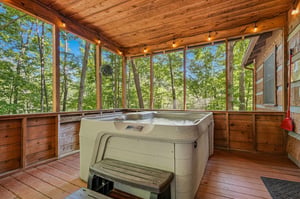 Soak in your private hot tub while surrounded by tranquil forest views through floortoceiling windows, all beneath warm string lights creating the perfect evening retreat.