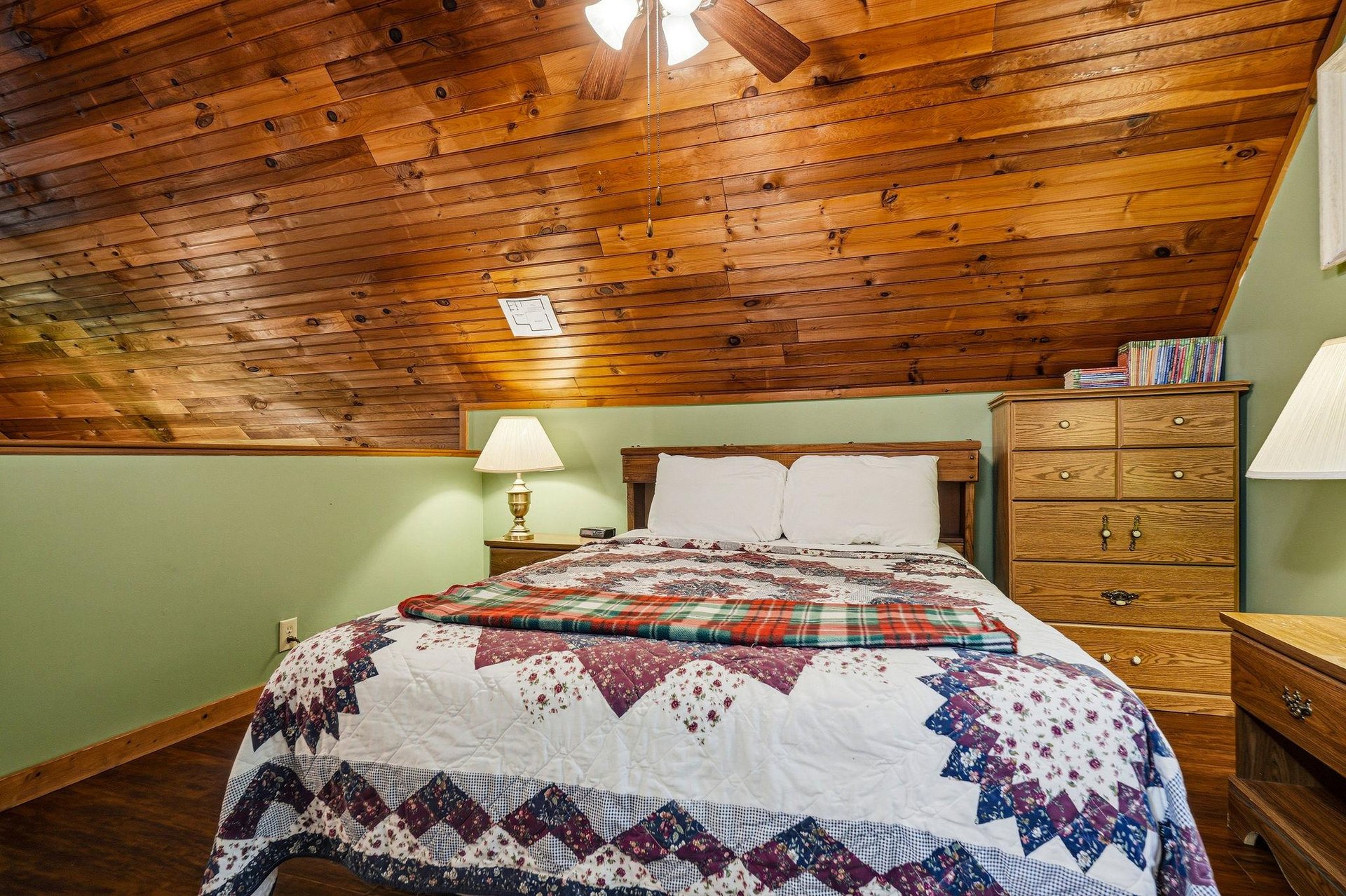 Cozy up under a handcrafted quilt in your rustic retreat, where warm wood beams create an intimate sanctuary for peaceful nights.