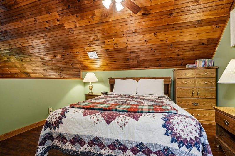 Cozy up under a handcrafted quilt in your rustic retreat, where warm wood beams create an intimate sanctuary for peaceful nights.