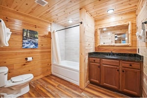 Unwind in your rustic cabin bathroom with warm wood walls, granite vanity, and a relaxing tubshower combo surrounded by cozy mountain lodge charm.