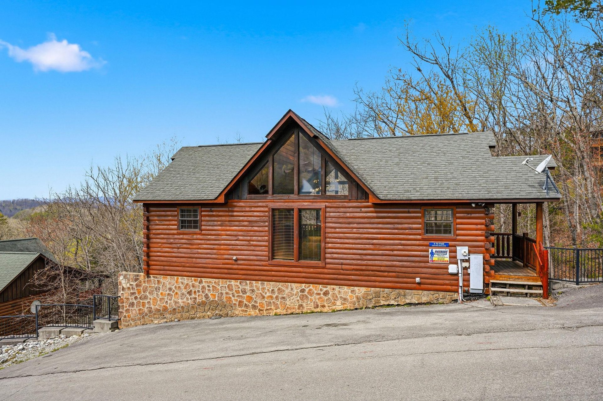 Charming log cabin with stone foundation nestled in the mountains, featuring large windows and scenic surroundings.