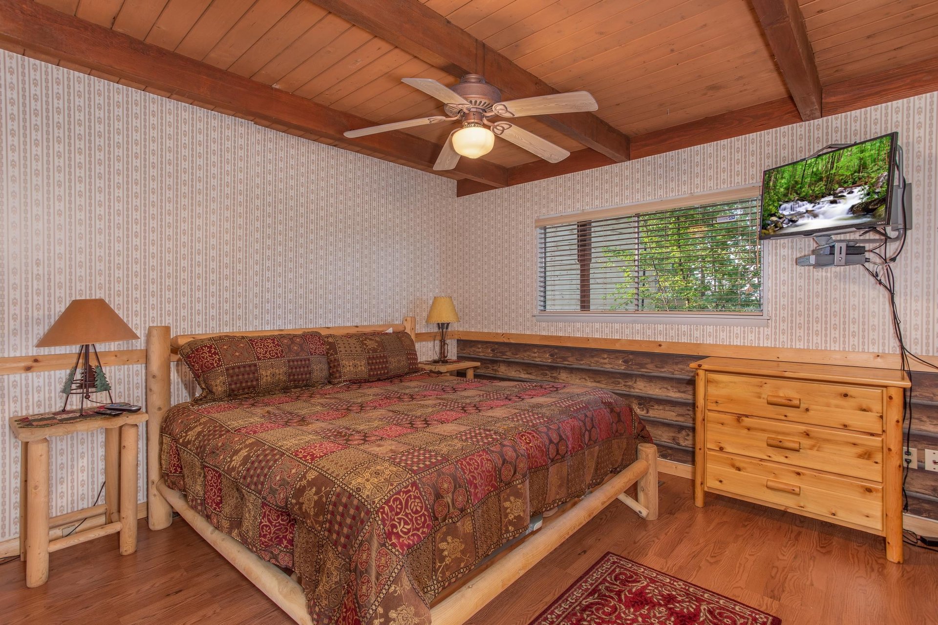 Bedroom with a kingsized log bed, dresser, and television at Bushwood Lodge, a 3bedroom cabin rental located in Gatlinburg
